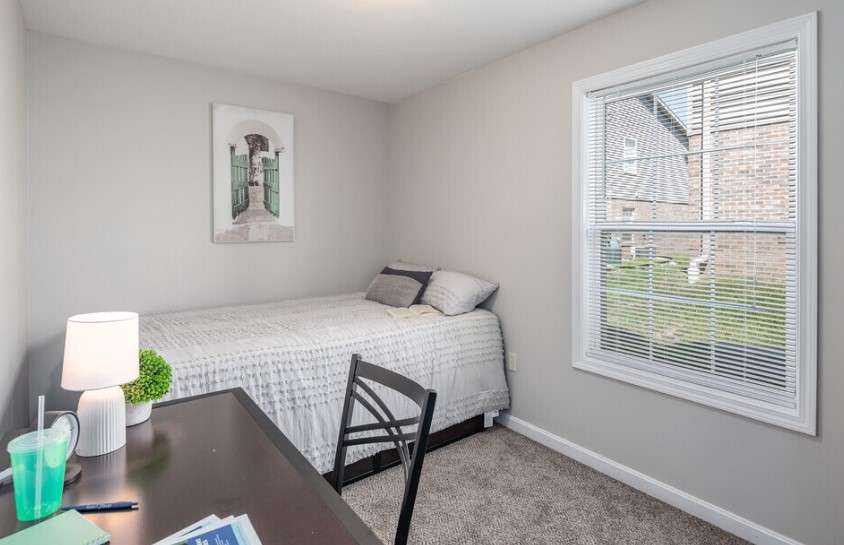 a small bedroom with a desk and a bed