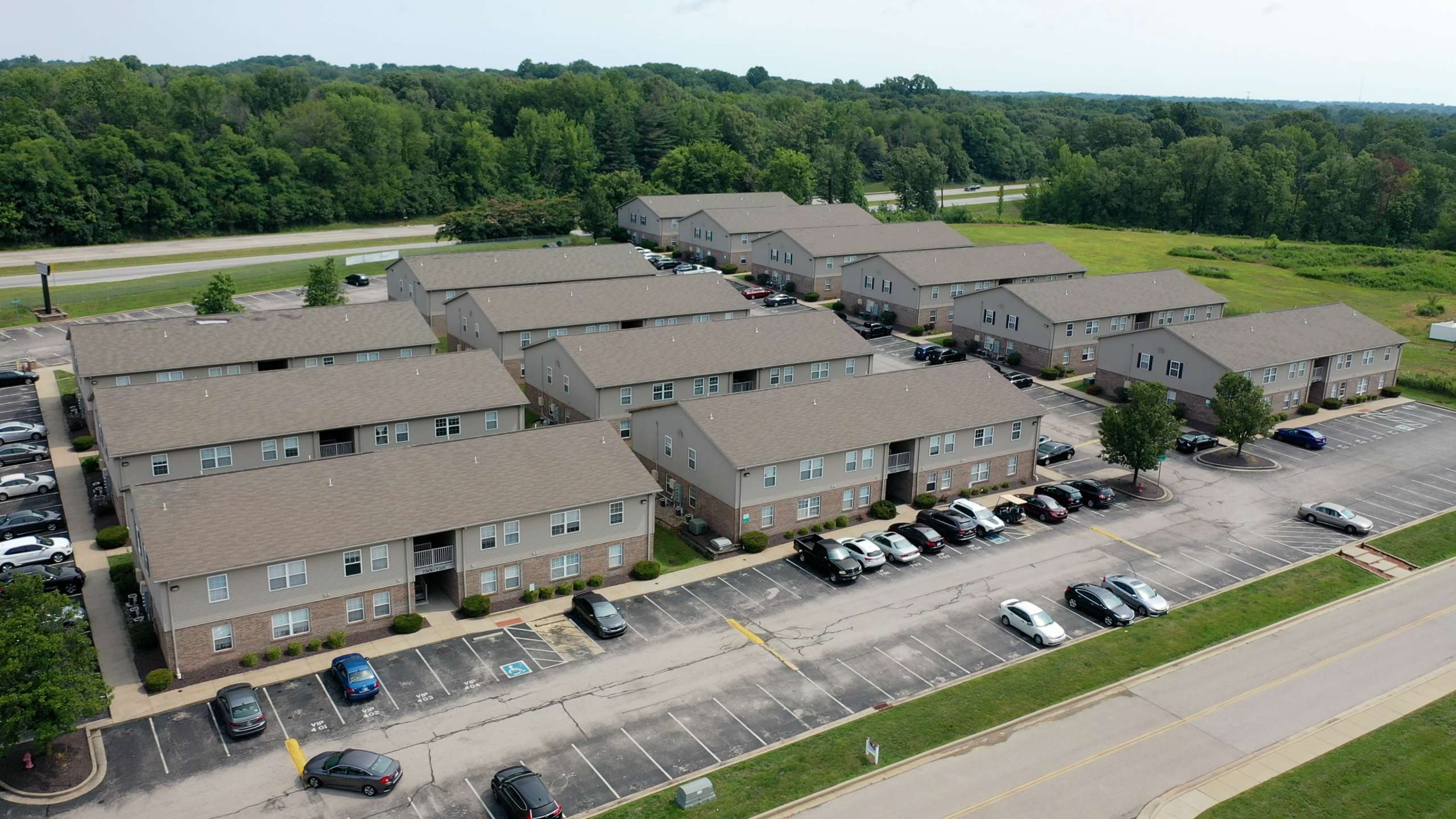 a group of apartments with parking lot and trees