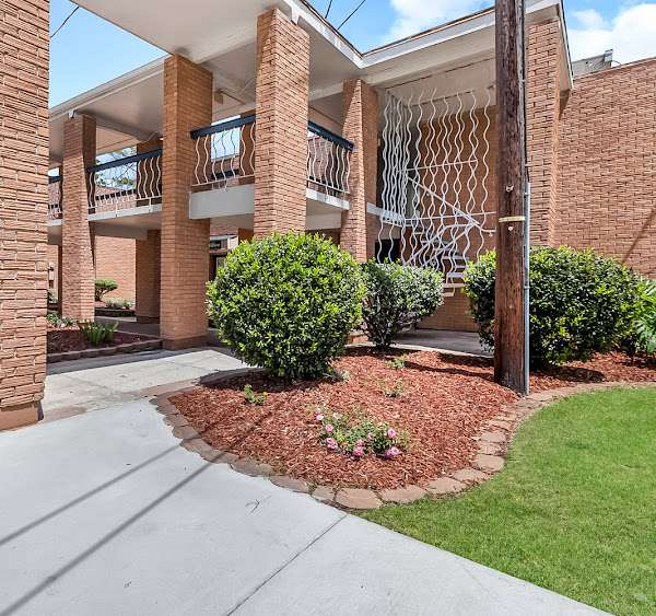 a brick building with a lawn and bushes