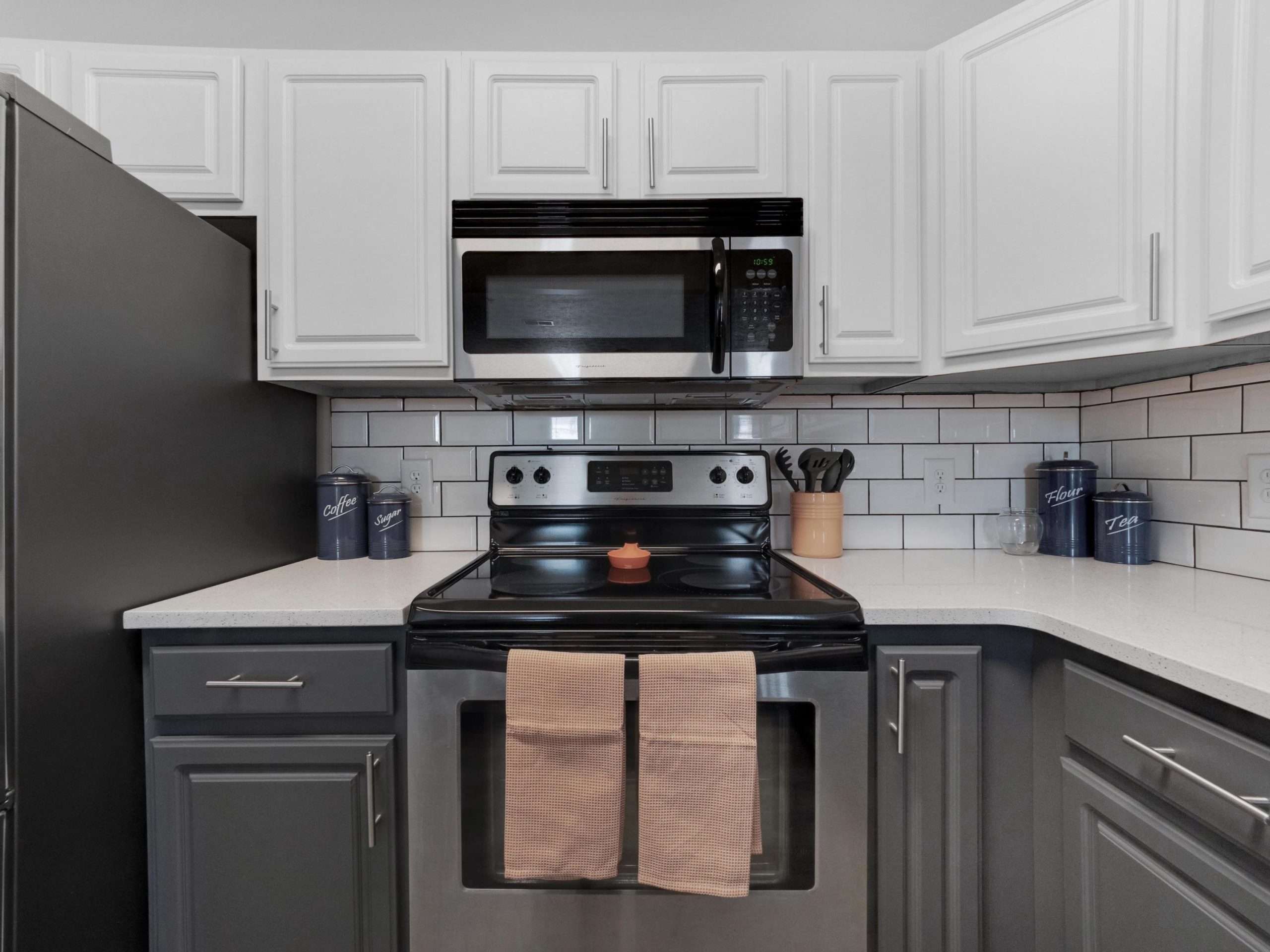 a kitchen with white cabinets and black appliances